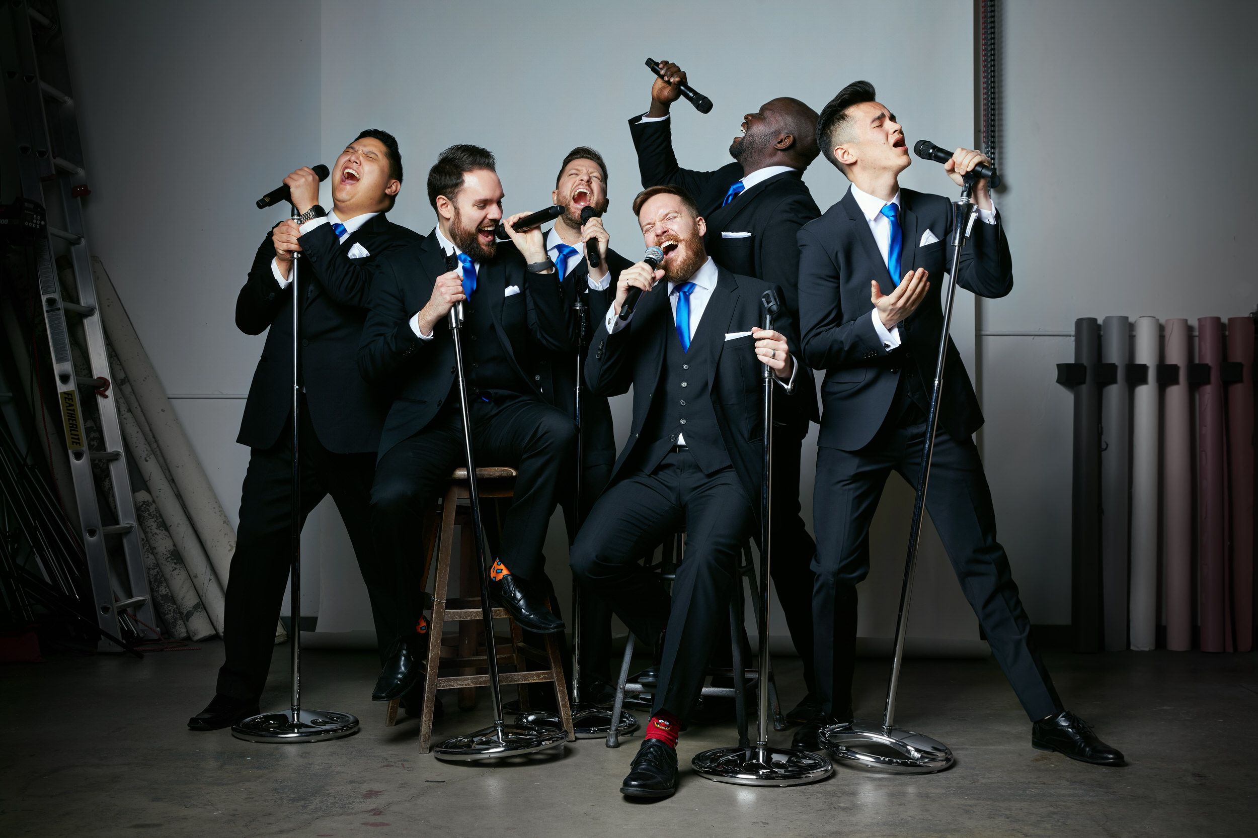 6 Minute Warning in black suits and blue ties, singing into vintage microphones in a studio